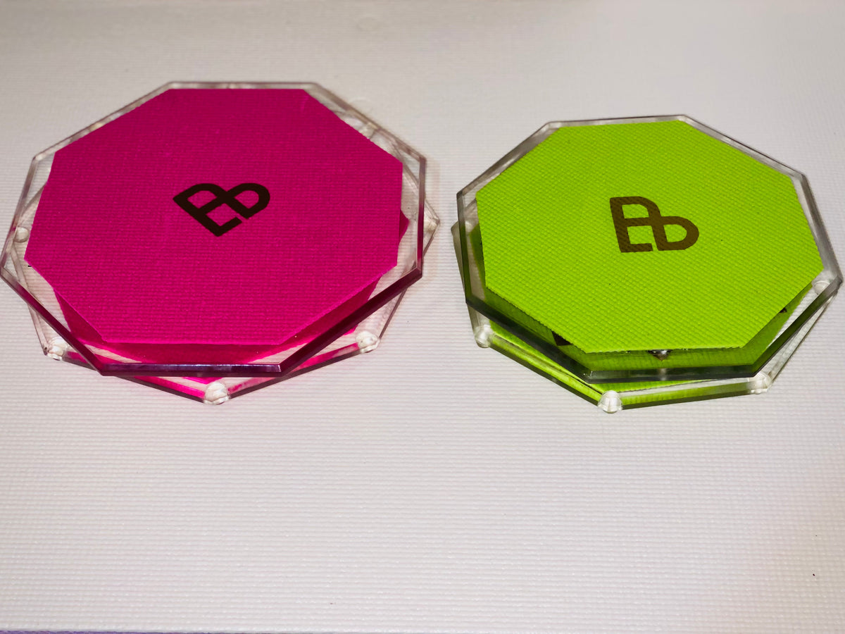 Two Bellenae spinning boards, one pink and one green, on a white background