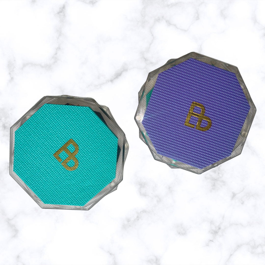 Two Bellenae spinning boards, one with a teal mat and one with a purple mat, on a white marble surface